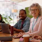 Educators smiling and talking together around a table during a professional learning conversation